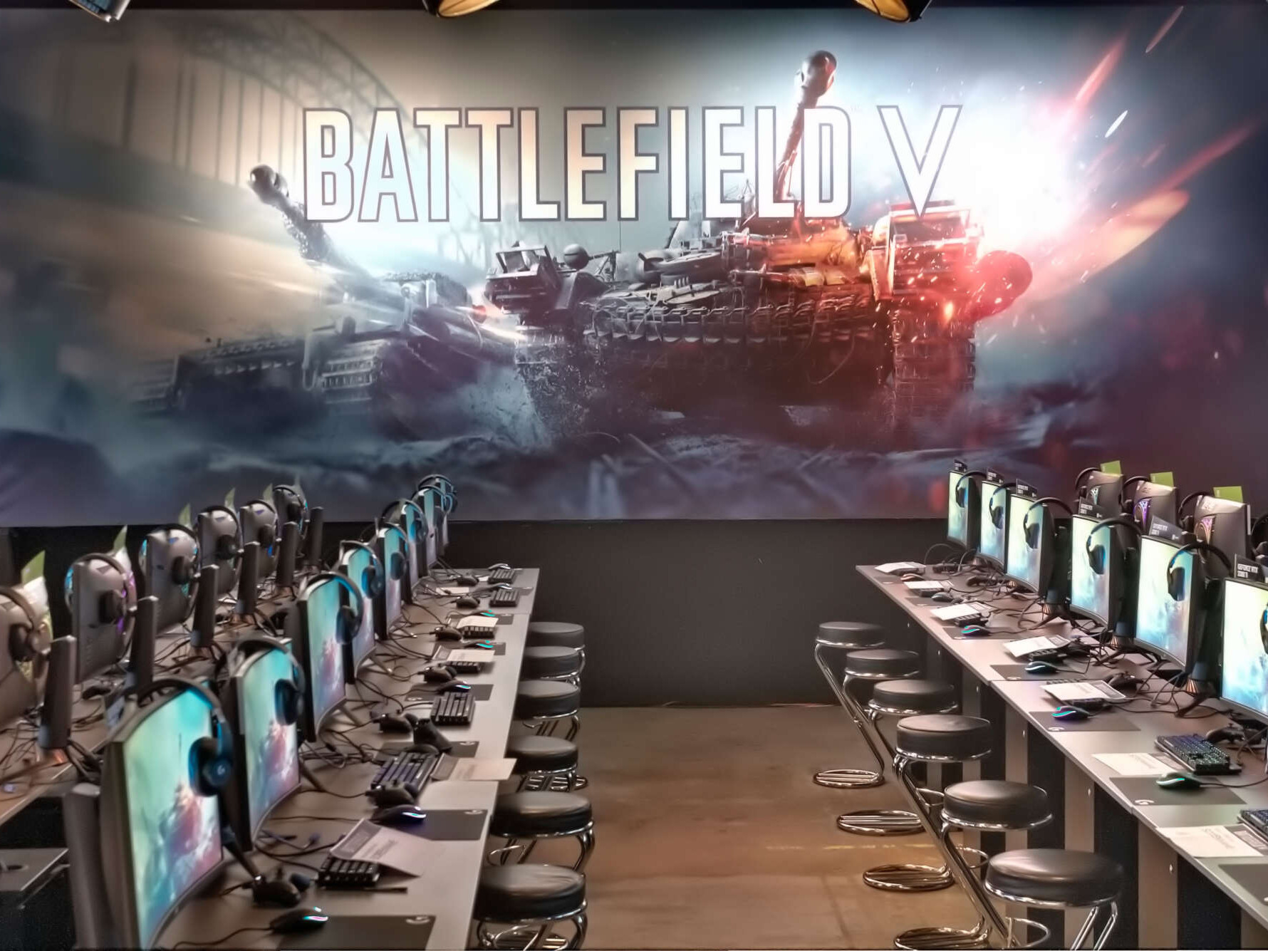 Hinter aufgereihten Gaming-PCs steht eine große Brandingwand, auf der zwei Panzer und ein Battlefield V Schriftzug zu sehen sind